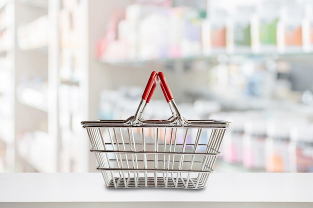 Empty shopping basket on pharmacy drugstore counter with blur shelves of medicine background