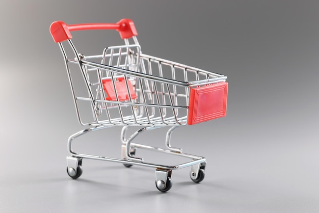 회색 배경에 대한 빈 쇼핑 카트는 제품을 수집하기 위한 컨테이너의 단일 미니어처 모델입니다.