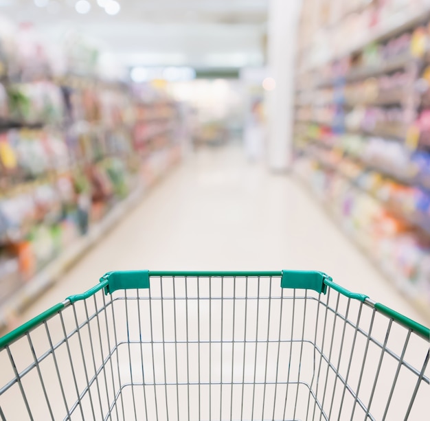 Photo empty shopping cart with abstract blur supermarket discount store aisle and product shelves interior defocused background