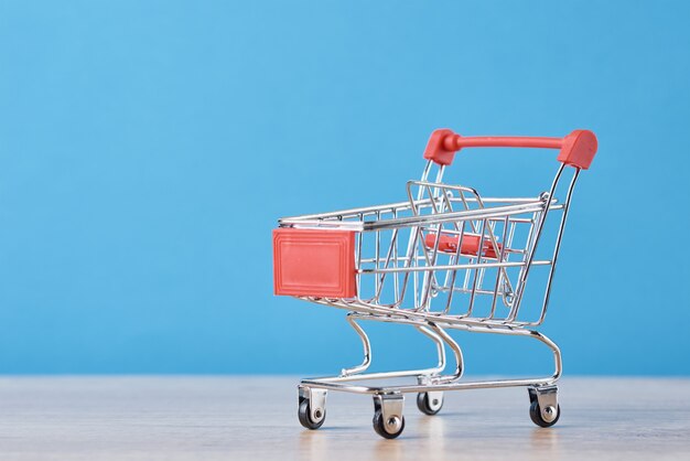 Empty shopping trolley cart on blue background. Shopping concept