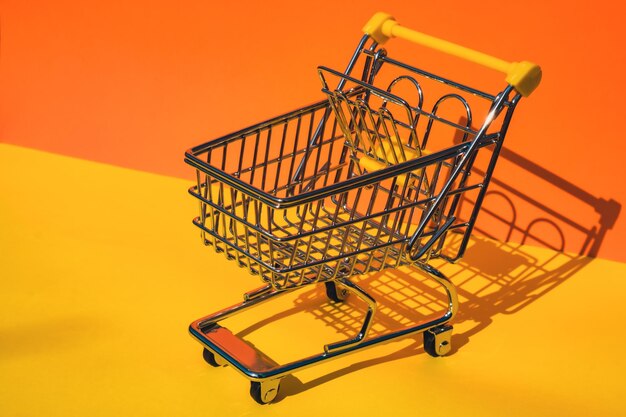Empty shopping trolley cart on colorful orange yellow background copy space for your text online