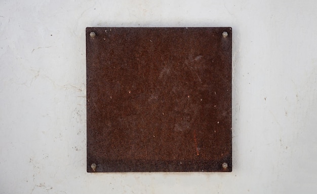 Empty sign plate rusty metal brown color mounted on white wall