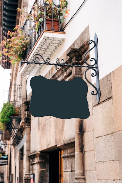 Photo empty signboard of a bizarre shape hangs on a beautiful forged pin on the facade of an old building