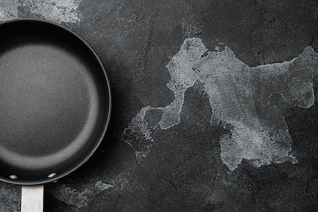 Empty skillet, frying pan set with copy space for text or food with copy space for text or food, top view flat lay, on black dark stone table background