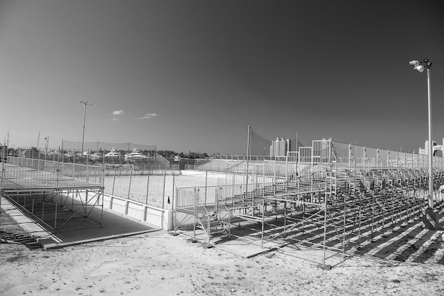 Empty small local stadium or arena with ground and training construction near tribunes sunny day outdoor with nobody on blue sky background