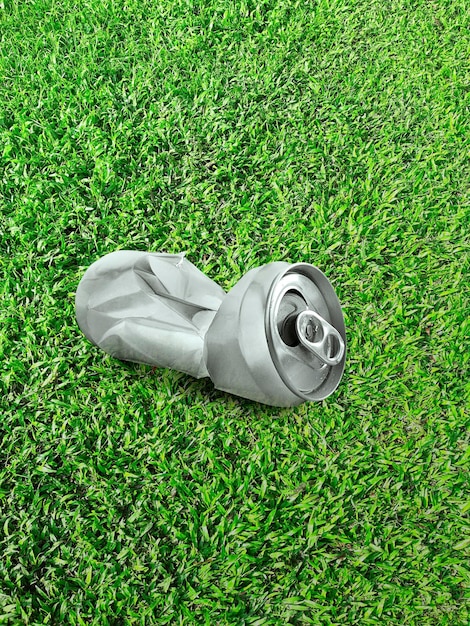 Empty soda or beer cans crushed waste can be recycled on the\
clear green grass turf closeup