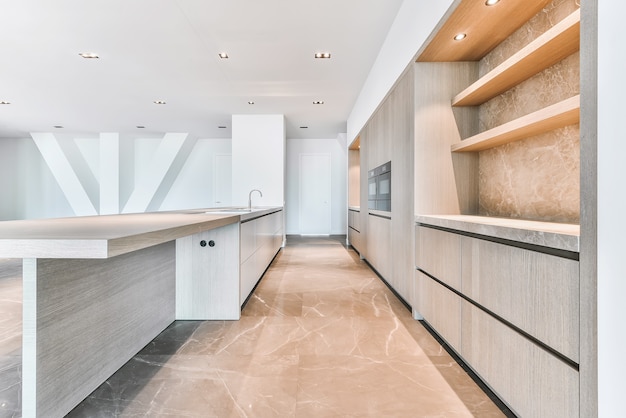 Empty spacious kitchen with contemporary minimalist cabinets in luxury penthouse apartment with tiled floor