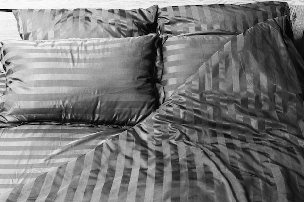 Фото Пустая расстеленная кровать с полосатым атласным постельным бельем крупным планом черно-белое фото