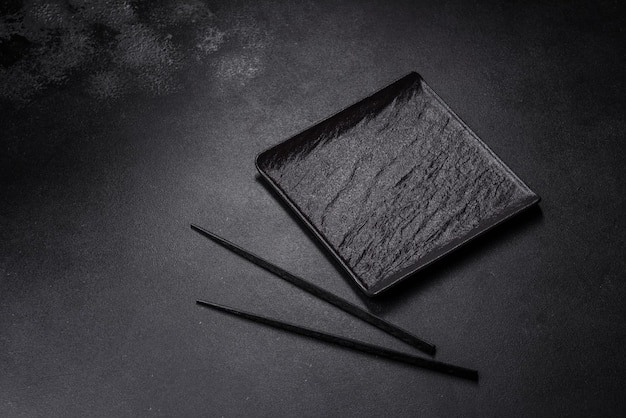 Empty square black plate on dark moody background with copy space