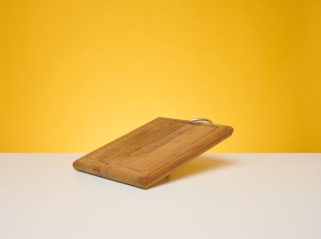 Empty square wooden cutting board on yellow background product display space