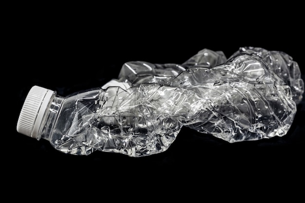 Empty, squashed water bottle isolated on black background