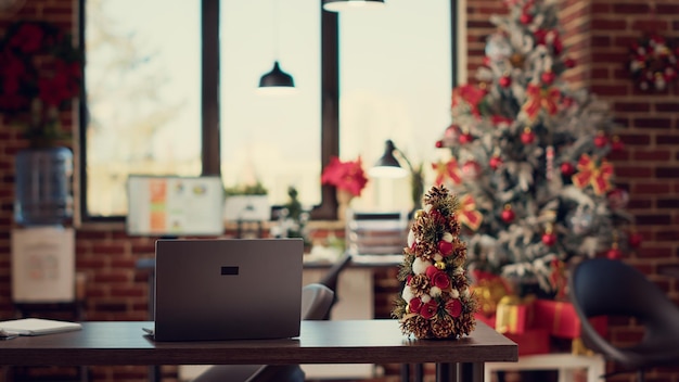 Empty startup office decorated with xmas ornaments and lights, used to celebrate winter season festivity. Interior decor with christmas tree and festive decorations for holiday party.