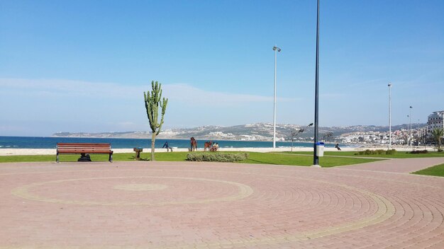 Empty street by beach against blue sky