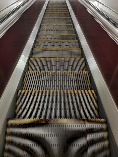 Empty supermarket escalator stairs with railings View from above