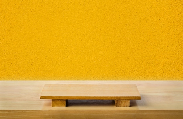 Фото Пустая доска для суши на деревянном столе с желтым цементным фоном. вид сверху на доску для графического дизайна интерьера или монтажа продукта.