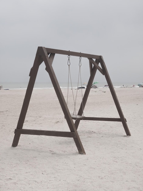 Empty swing at beach against clear sky