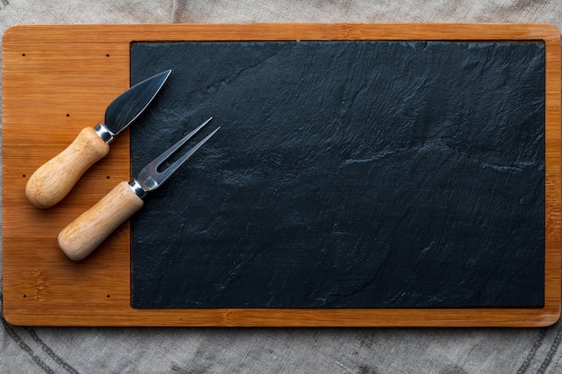 Empty table for cheeses and other openings. Copyspace. Blackboard Fork and knife for cheese.Top View.