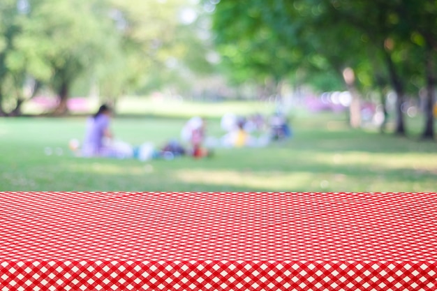 Photo empty table and red tablecloth over blur park with people background