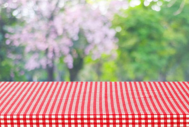 Empty table and red tablecloth with blur green leaves bokeh