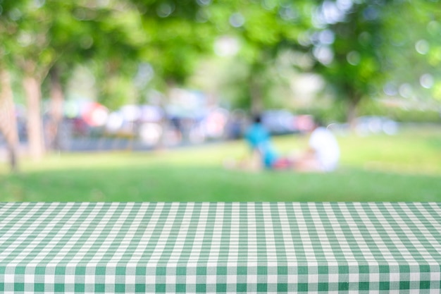 写真 人々とbokehの背景、食品と製品のディスプレイのモンタージュとぼかし公園の上に緑のテーブルクロスと空のテーブル