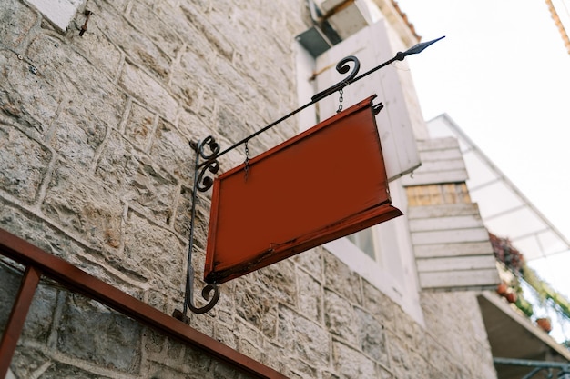 Foto una tavoletta vuota è appesa a un cartello forgiato sulla facciata in pietra di una vecchia casa