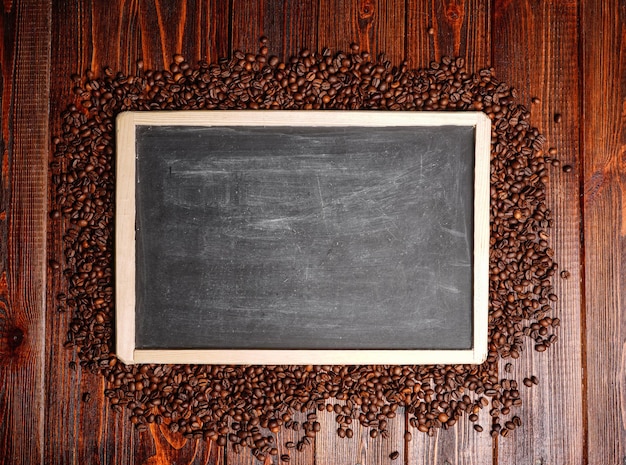 Empty template frame made from coffee beans. Wooden background black board with coffee seeds and copy space. High quality photo