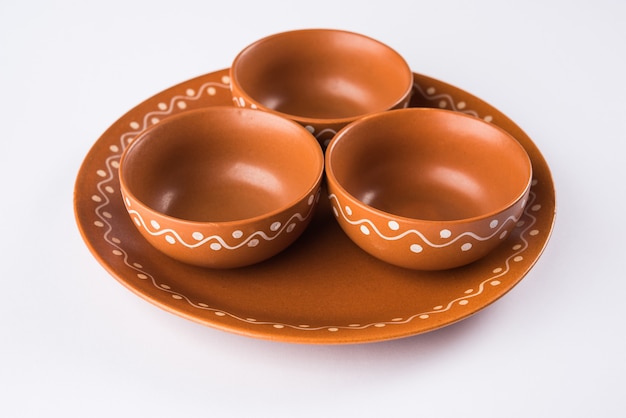 Empty terracotta dinnerware or dining set like plate, soup bowl, serving bowl, glass made up of brown clay, isolated over white