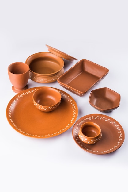 Пустая терракотовая посуда или обеденный набор, такой как тарелка, суповая миска, сервировочная миска, стакан из коричневой глины, изолированные на белом