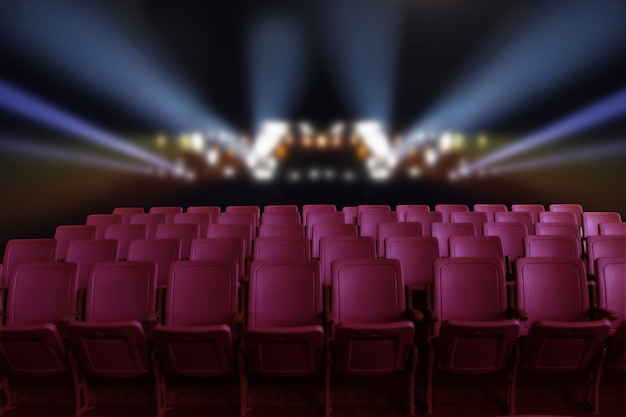 Empty theater auditorium or cinema with red seats and lighting behind