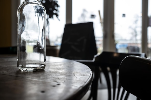 Empty transparent bottle of drinking water stands on a round wooden table