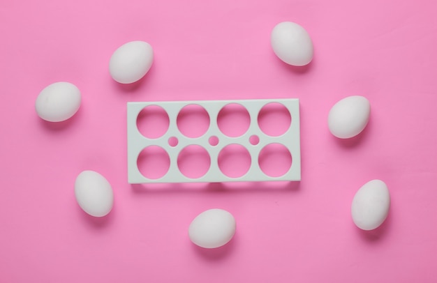 Empty tray and chicken eggs on pink background. Minimalism food concept. Top view