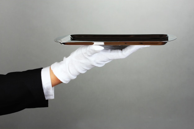 Empty tray in hand waiter on grey background