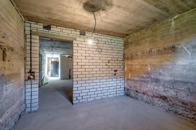 Empty unfurnished basement room with minimal preparatory repairs interior with white brick walls