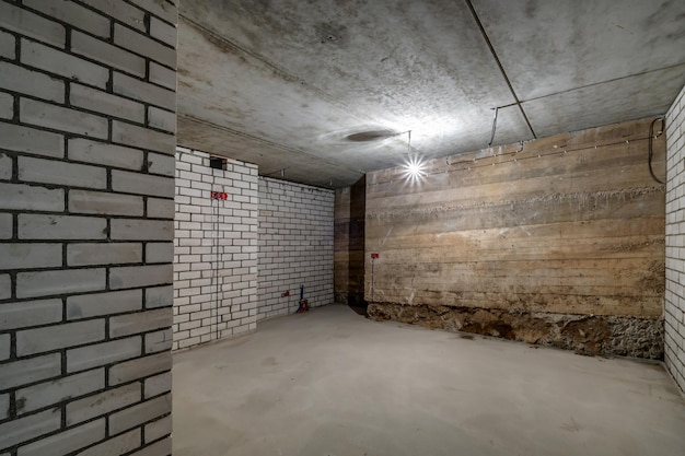 Empty unfurnished basement room with minimal preparatory repairs interior with white brick walls