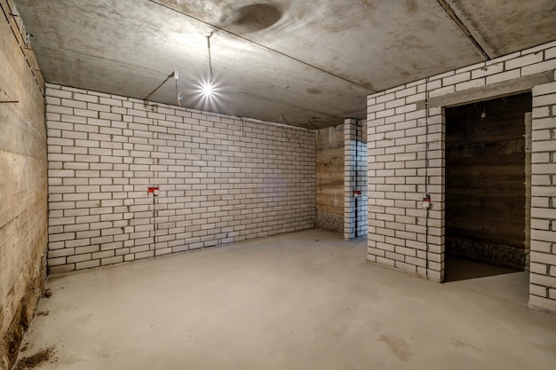 Empty unfurnished basement room with minimal preparatory repairs interior with white brick walls