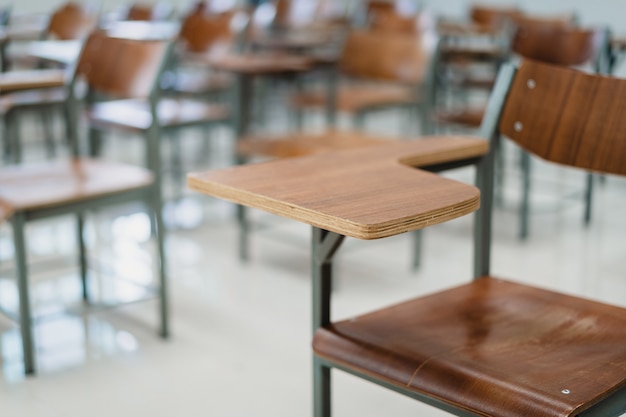 Empty university classroom with many wooden chairs. Wooden chairs well arranged in college classroom. Empty classroom with vintage tone wooden chairs. Back to school concept.