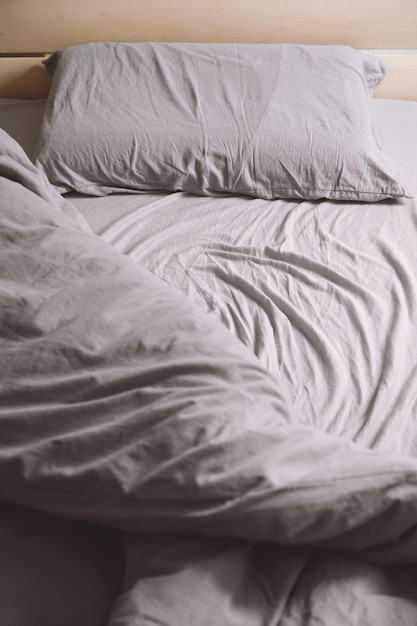 Empty unmade bed with crumpled bedding or bedclothes