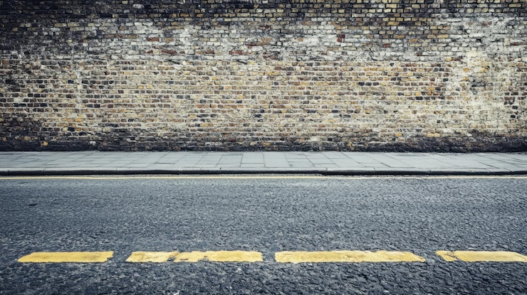 Photo empty urban street with a grunge warehouse brick wall in the background capturing a rugged industrial vibe for street photography or product displays