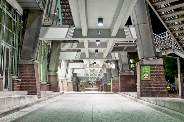 Empty walkway below bridge by building in city