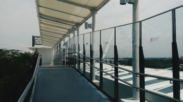 Empty walkway by glass windows in city