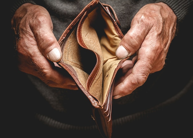 Photo empty wallet in the hands of an elderly man