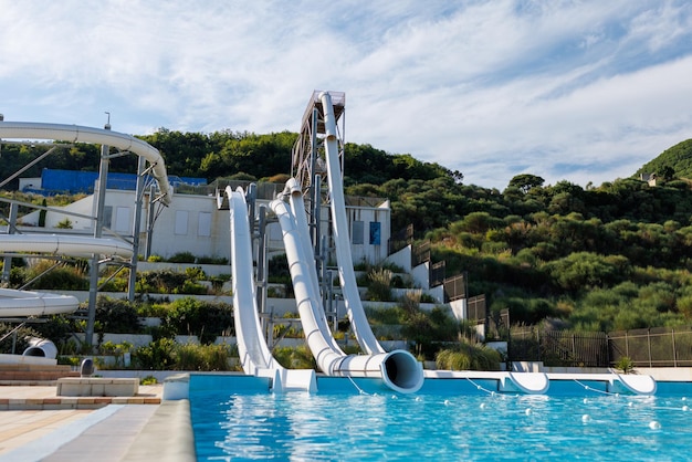 Empty water park with high white slides pools and white sun loungers