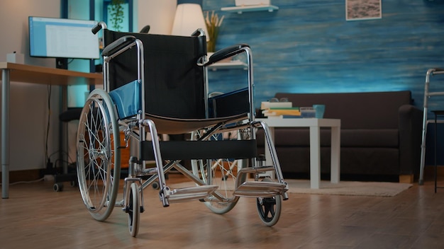 Empty wheelchair in living room to help with mobility and\
transportation. nobody in space with walking support equipment to\
give aid to person with physical disability. accessibility\
object