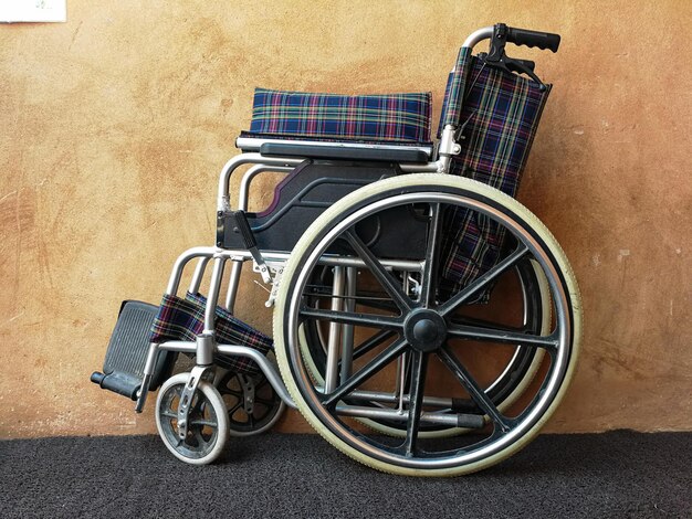 Empty wheelchair near cement wall indoors Space for text