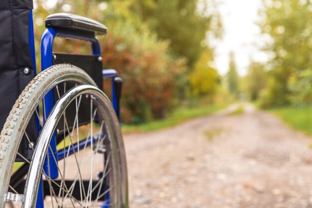 Empty wheelchair standing on road waiting for patient services. Invalid chair for disabled people parked outdoor in nature. Handicap accessible symbol. Health care medical concept.