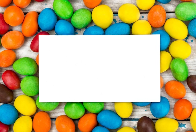 Scheda bianca vuota con caramelle colorate sul tavolo vista dall'alto