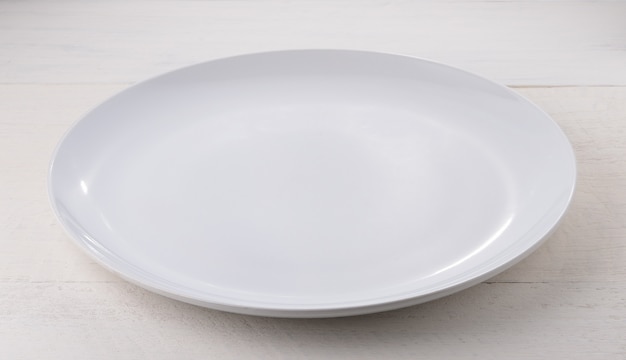 Empty white ceramic plate on wooden table