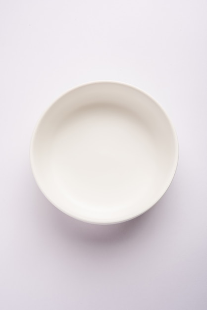 Empty white ceramic serving bowl, isolated over white or gray surface