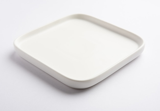 Пустая белая керамическая квадратная тарелка, изолированная на белой поверхности