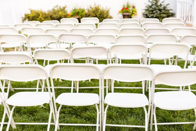 Empty white chairs before wedding ceremony.